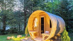 A wooden cabin with a curved roof, a small porch, and a bench.