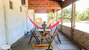 A covered outdoor dining area with wooden tables and chairs, a hammock, and potted plants. - Pousada Mar das Gaivotas (Cajueiro da Praia)