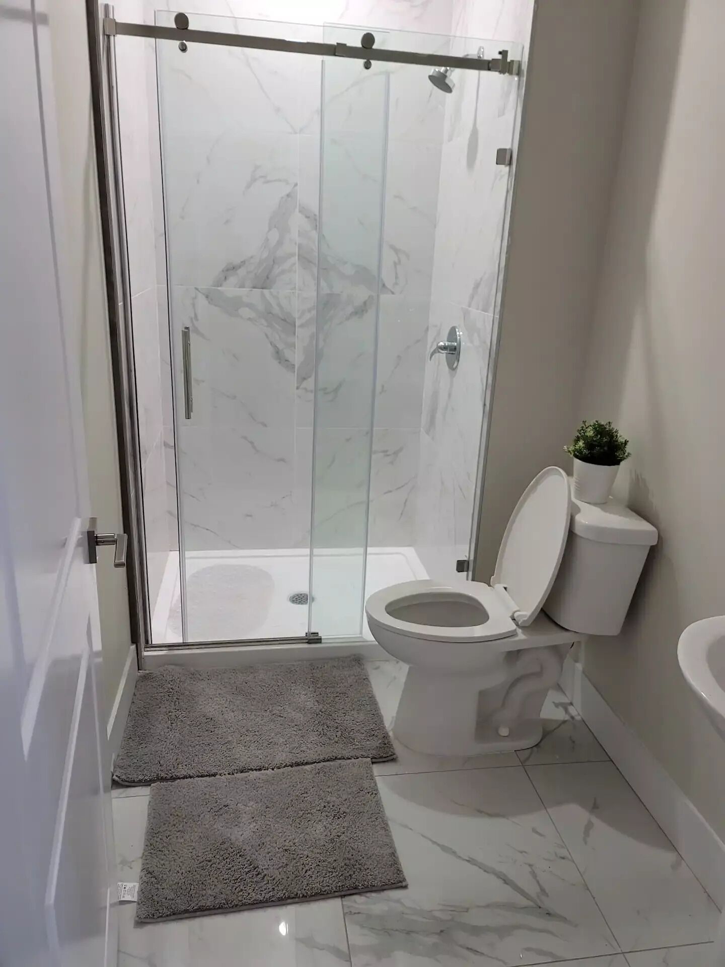 Un baño con ducha de mampara de vidrio, inodoro y lavabo.