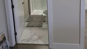Ein modernes Badezimmer mit einer Duschkabine aus Glas, einer Toilette und einem Boden mit Marmorplatten.