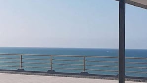 Vista al mar con cielo despejado, barandilla de metal y plataforma de concreto.