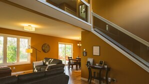 A spacious living area with a high ceiling, a staircase, and a dining area. - Nature Oasis: Waterfront, pet friendly, kayaks, SUPs, dock, amenities galore (Kingsville)