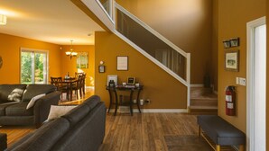 A spacious living area with a wooden floor, a staircase, and a dining area with a table and chairs. - Nature Oasis: Waterfront, pet friendly, kayaks, SUPs, dock, amenities galore (Kingsville)