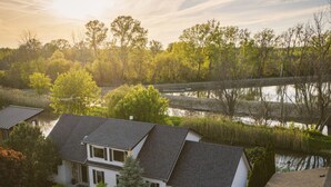 A two-story house with a garage, a driveway, and a pond in the background. - Nature Oasis: Waterfront, pet friendly, kayaks, SUPs, dock, amenities galore (Kingsville)