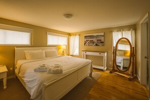 A neatly arranged bedroom with a large bed, bedside tables, a dresser, a mirror, and a painting on the wall. - Sauna, stunning views of Lake Erie, lakefront retreat (Kingsville)
