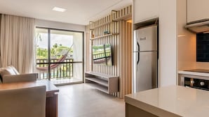 A modern kitchen with a built-in refrigerator, a flat-screen TV mounted on a wooden panel, and a dining area with a table and chairs. - Beach Class Resort  (Ipojuca)