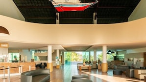A spacious lobby with a check-in counter, seating areas, and a large window offering a view of the outdoors. - Beach Class Resort  (Ipojuca)