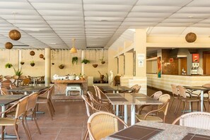 A restaurant with wicker chairs and tables, a counter with a cash register, and hanging plants. - Beach Class Resort  (Ipojuca)