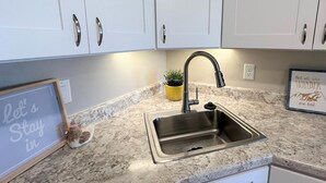 A modern kitchen with white cabinets, a stainless steel sink, and a marble countertop. - Sweet Suite Retreat,  Studio apartment in Cedar City (Enoch)