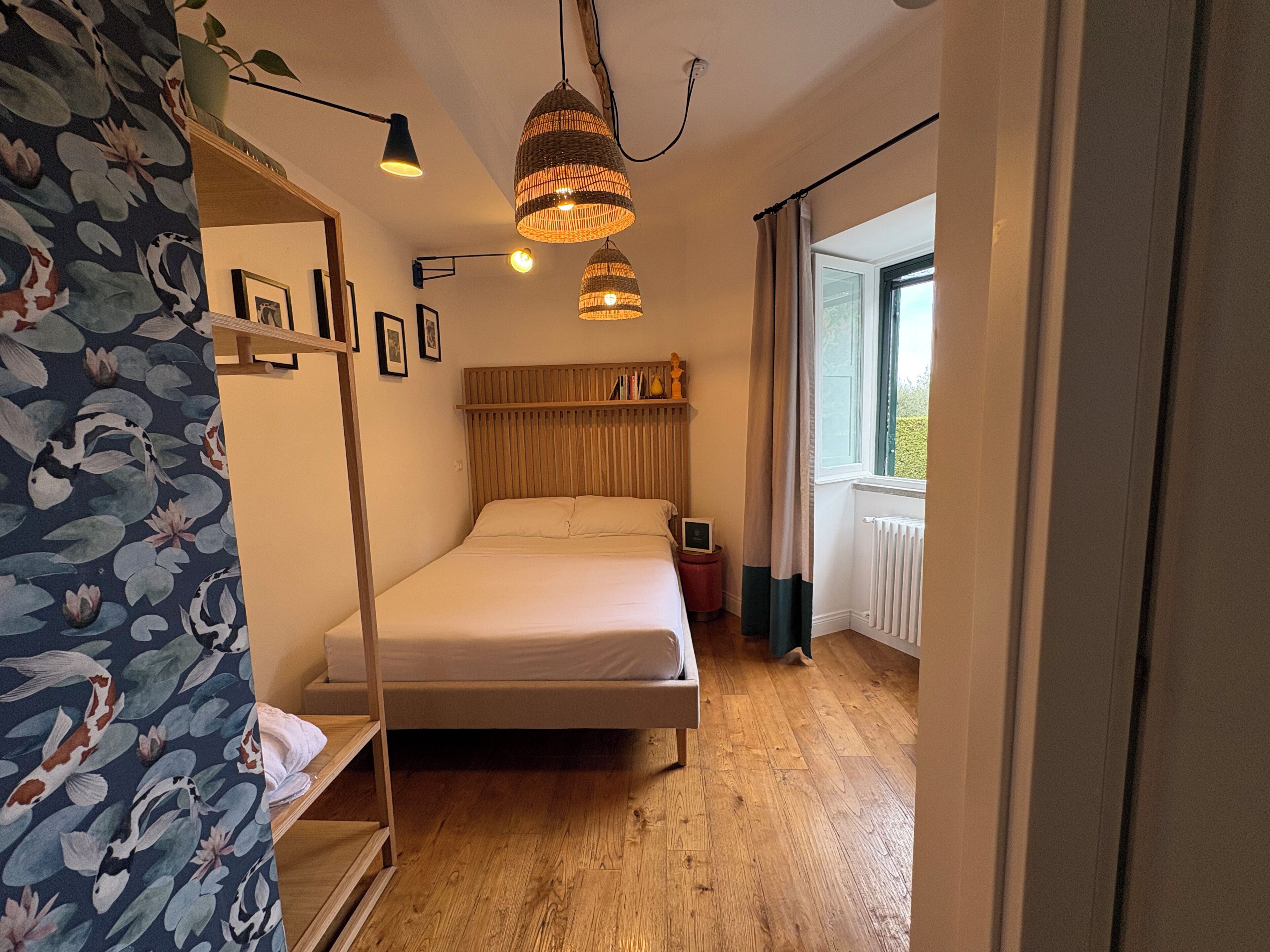 Une chambre à coucher avec un lit superposé, une table de chevet, un luminaire suspendu et une fenêtre avec des rideaux.
