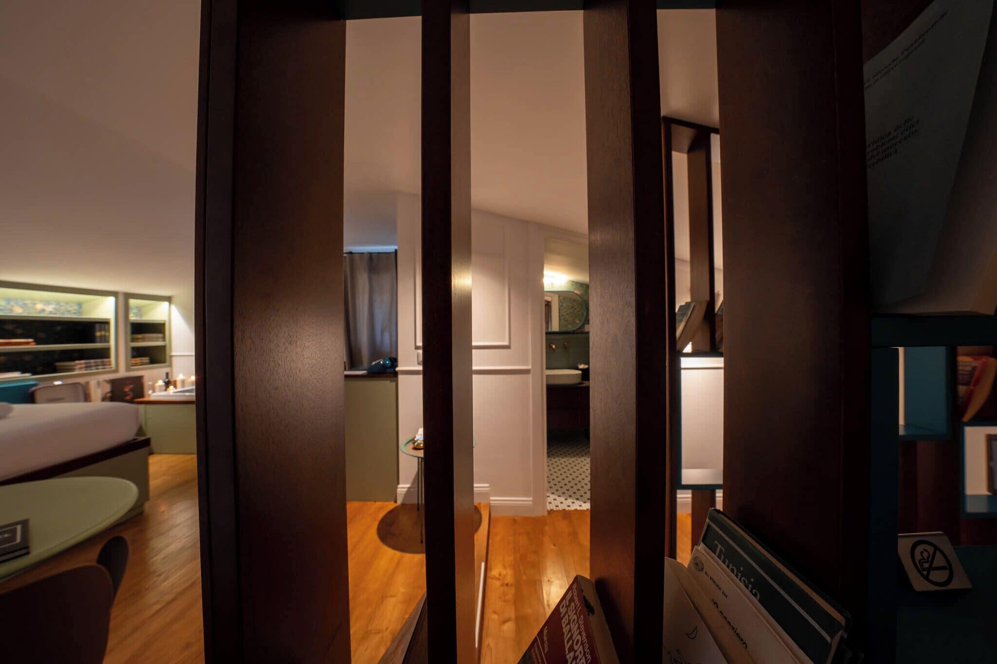 A hotel room with a bed, a desk, and a view of the hallway.