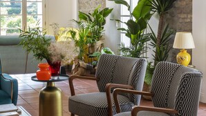 A cozy living room with patterned chairs, a small round table with cups, and potted plants. - Giardini Penelope Resort e Spa (Ciampino)