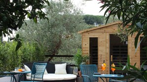 An outdoor seating area with a round sofa, two chairs, and a table with drinks. - Giardini Penelope Resort e Spa (Ciampino)