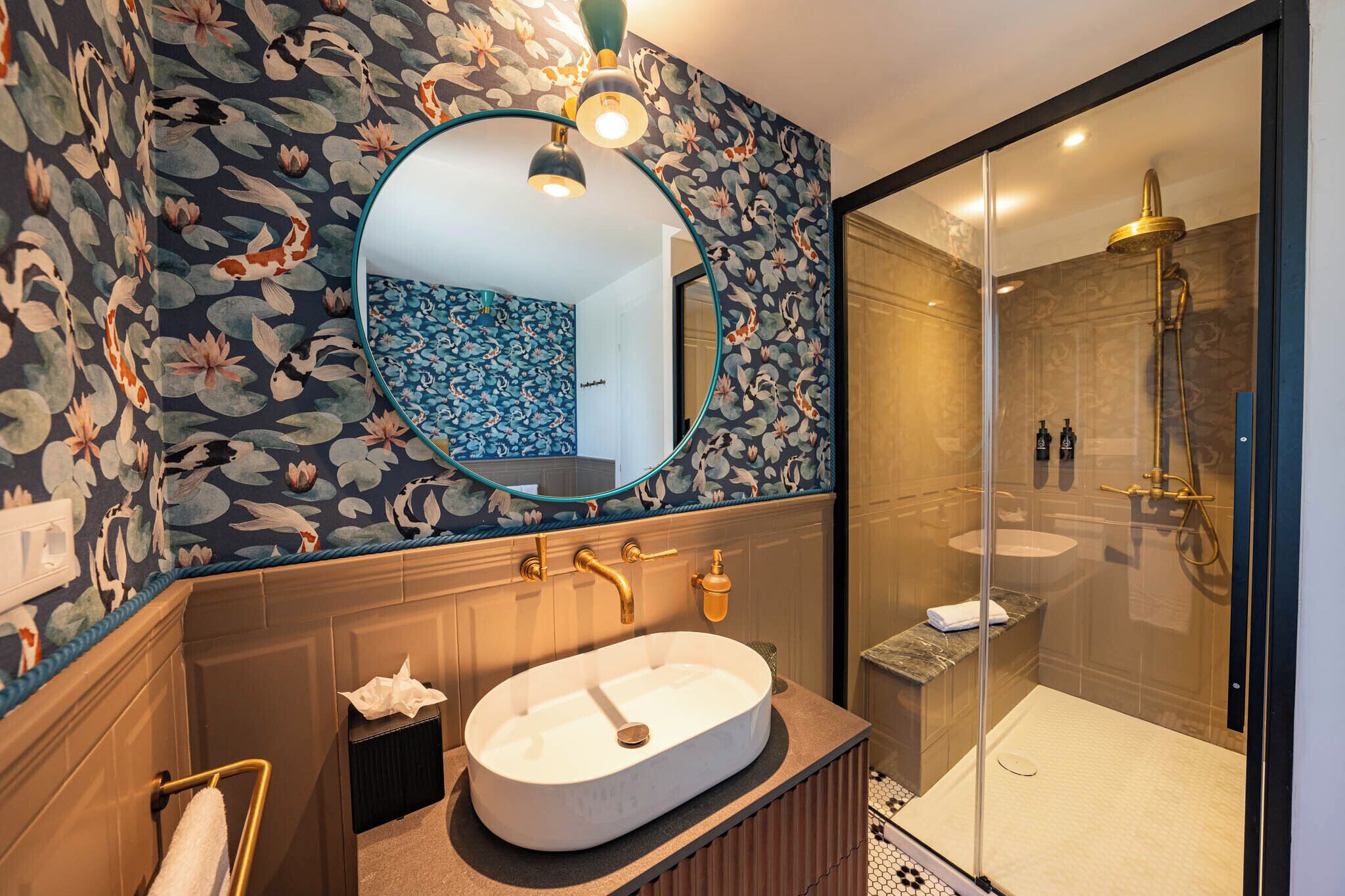 Une salle de bain avec un grand lavabo ovale, un miroir et un espace douche.