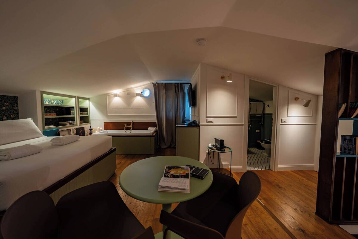 Habitación de hotel pequeña con una cama, un escritorio, una mesa verde y una silla.