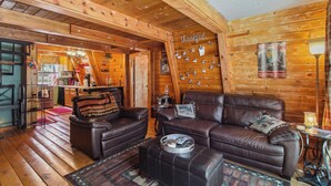 Un intérieur de chalet chaleureux avec des murs en bois, un canapé en cuir et un coin repas.