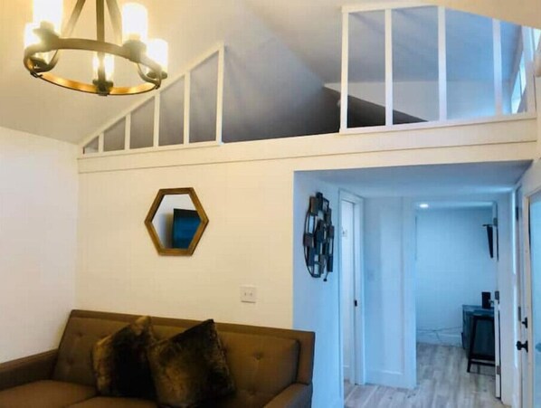 Ein Wohnzimmer mit einem braunen Sofa, einem sechseckigen Spiegel und einer Chandelier.