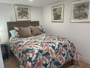 Ein Schlafzimmer mit einem Bett, einem Nachttisch und drei gerahmten Kunstwerken an der Wand.