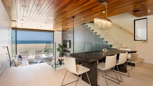 Una cucina moderna con una grande isola, una scala in vetro e vista sulla spiaggia.