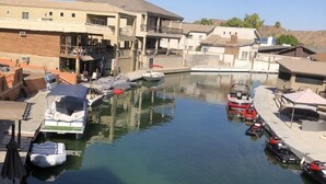 Ein Yachthafen mit vertäuten Booten, einem rosa Luftmatratze im Wasser und Gebäuden mit Balkonen.