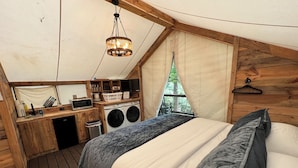 A cozy bedroom with a large bed, a wooden desk, and a washing machine.