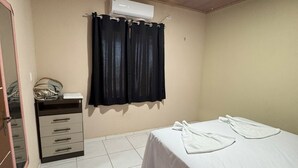 A bedroom with a bed, a dresser, a mirror, and an air conditioning unit. - Chalé panulirus (Icapuí)