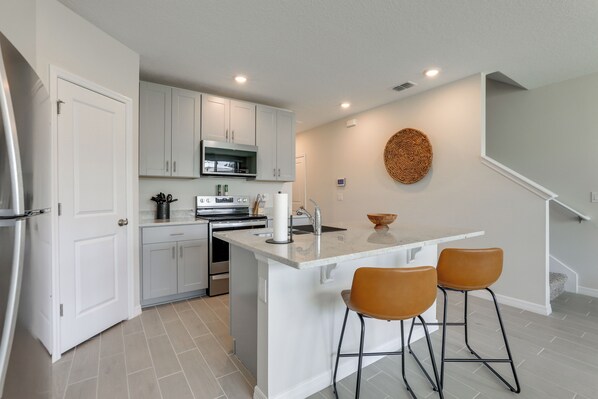 Enjoy cooking in this kitchen with a central island, bar stools, and stainless steel appliances.