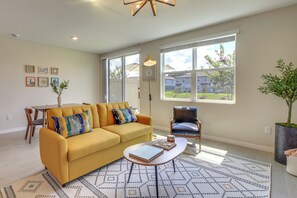 Relax in this stylish living room with a sofa, armchair, and coffee table, offering a view of the neighborhood through large windows.