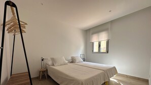A bedroom with two beds, a wooden chair, a small bedside table, and a window with a view. - Maravilloso Piso a Estrenar en el Corazón de la Ciudad (Vila-real)