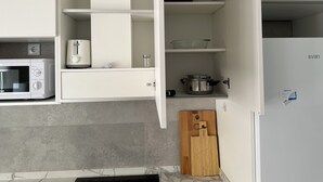 A kitchen with white cabinets, a microwave, a toaster, a wooden cutting board, and a stainless steel pot. - Maravilloso Piso a Estrenar en el Corazón de la Ciudad (Vila-real)