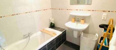 A bathroom with a bathtub, sink, toilet, and a small mirror.