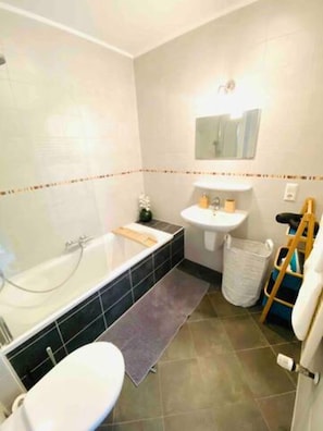 A bathroom with a bathtub, sink, toilet, and a small mirror. - Charming Duplex in Center w. 2 Terraces (Luxembourg City)