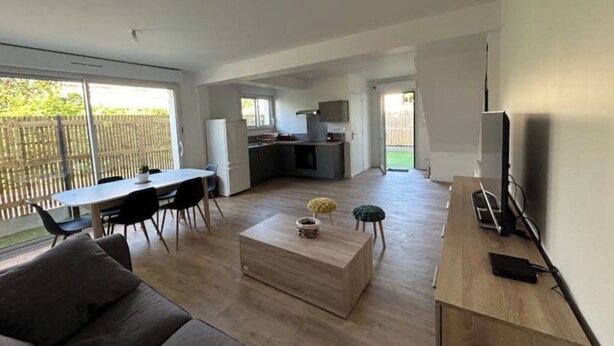 Amplia sala de estar con una mesa de comedor, sofá y cocina al fondo.
