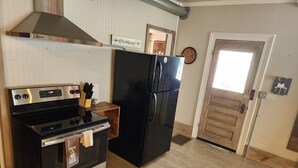 A kitchen with a stainless steel stove, black refrigerator, and wooden cabinets. - Unwind at the Lotus house Opal suite. (Lansing)