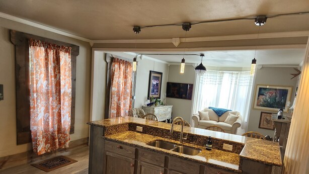 A kitchen with granite countertops, wooden cabinets, and a central island with a sink. - Unwind at the Lotus house Opal suite. (Lansing)