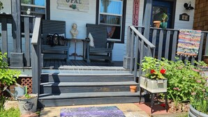 A porch with a bench, a small table with a statue, and a sign that reads "OPAL". - Unwind at the Lotus house Opal suite. (Lansing)