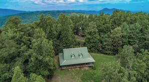 Situated in a secluded forest, this cabin offers a peaceful retreat surrounded by trees and a distant mountain range.