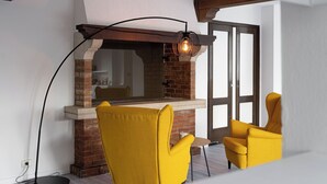 A modern living room with a brick fireplace, yellow chairs, and a floor lamp. - Grünwald (Salorno)