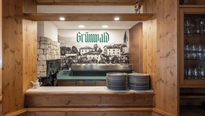 A restaurant interior with a wooden theme, a stone wall, and a cityscape mural. - Grünwald (Salorno)