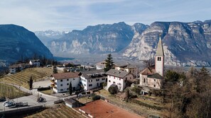 A village with traditional architecture, a church with a bell tower, and mountainous terrain in the background. - Grünwald (Salorno)