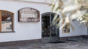 A pizzeria restaurant with a stone-tiled entrance and a glass door. - Grünwald (Salorno)