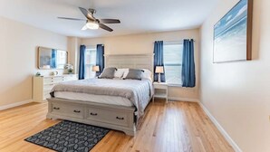 A bedroom with a bed, bedside tables, a ceiling fan, a window with curtains, and a painting on the wall. - Perfect Getaway @ CWE- Entire Home + Free Parking Near Fox, Universities & More! (St. Louis)