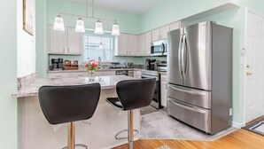 A modern kitchen with a stainless steel refrigerator, white cabinets, and a marble countertop. - Perfect Getaway @ CWE- Entire Home + Free Parking Near Fox, Universities & More! (St. Louis)