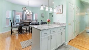A kitchen with a marble island, white cabinets, and a dining area with a table and chairs. - Perfect Getaway @ CWE- Entire Home + Free Parking Near Fox, Universities & More! (St. Louis)