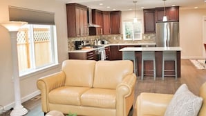 A modern kitchen with dark wood cabinets, a stainless steel refrigerator, and a central island with bar stools. - Charming, Brand New Home in Greenlake, 4br3ba (Seattle)