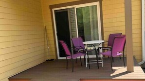 A covered patio with a table and chairs, a sliding glass door, and a set of steps leading to the door. - Charming, Brand New Home in Greenlake, 4br3ba (Seattle)