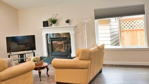 A living room with a fireplace, a television, and two sofas. - Charming, Brand New Home in Greenlake, 4br3ba (Seattle)