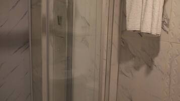 Une salle de bain avec une douche à parois de verre, des toilettes et un porte-serviettes avec des serviettes pliées.