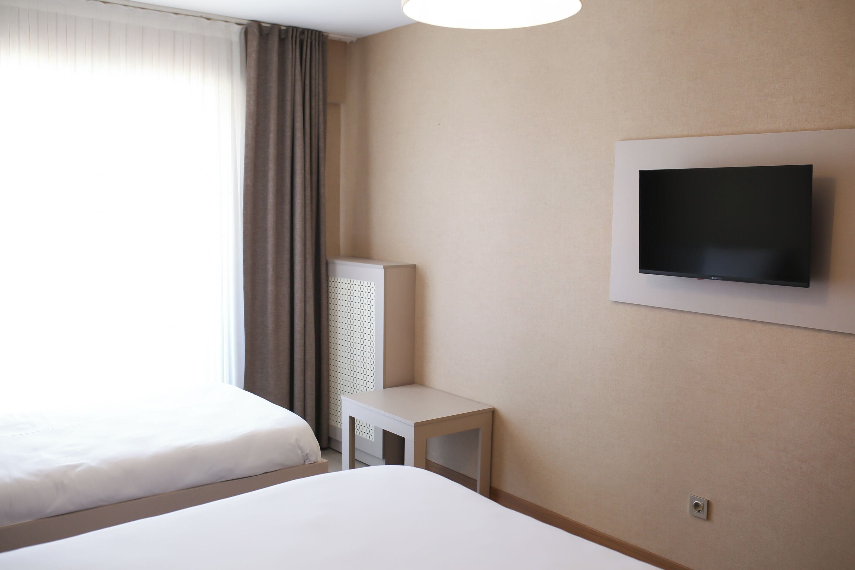 Una habitación de hotel con dos camas, un televisor montado en la pared y una mesita.