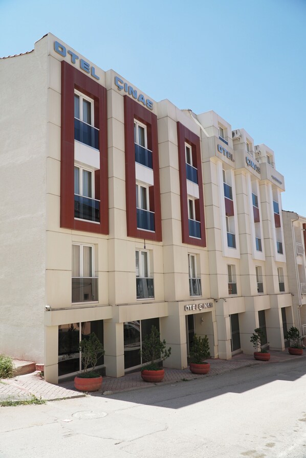 Un edificio de hotel de varios pisos con fachada color beige y detalles en rojo.